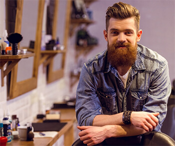Man in barbershop with good hair and neatly trimmed beard.
