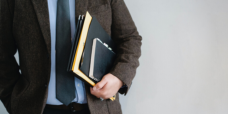 Close up of business man holding a folder and notebook.