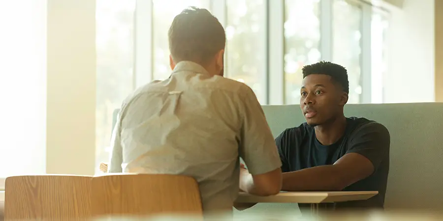 Two people discussing face to face in a meeting, demonstrating communication and active listening skills.