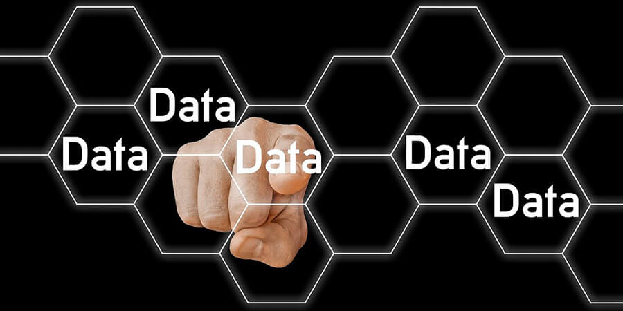 A conceptual image featuring a hand pointing forward toward the viewer, overlaid with a white hexagonal grid containing the word Data in several of the cells against a black background.