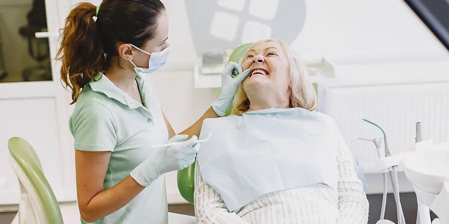 A dental professional examining a mature female patient.