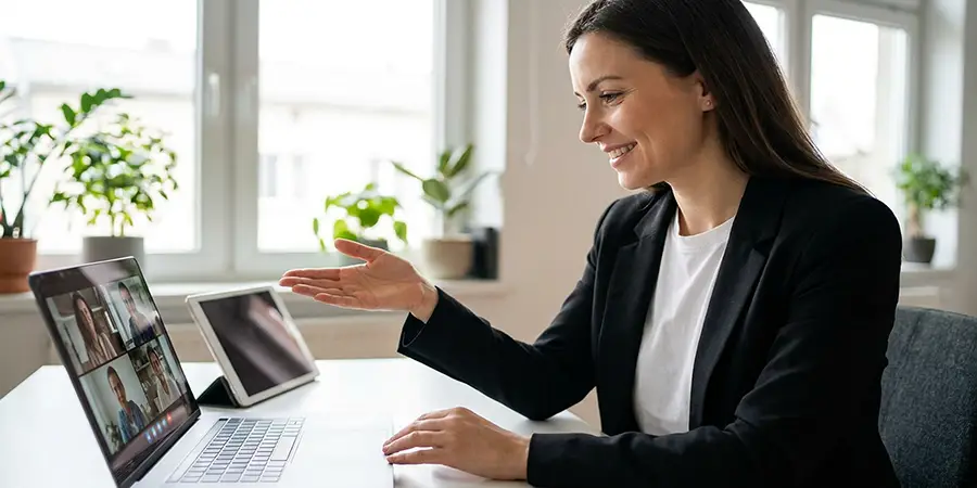 A professional in a black blazer smiling warmly during a video call to emphasize communication skills