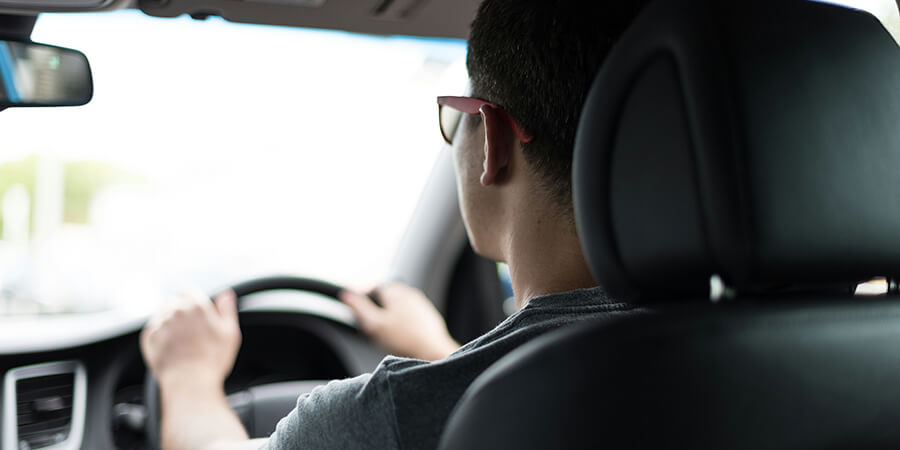 Person driving a car in bright conditions.