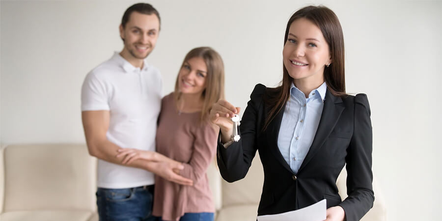 Mortgage broker and clients with broker holding up a set of keys.