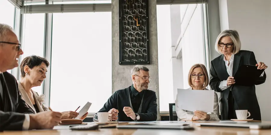 A group of executive leaders reviewing documents during a meeting in a modern office.