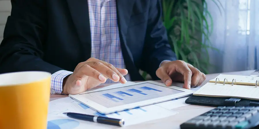 Professional reviewing documents at a desk on a tablet.