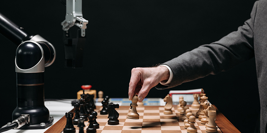 A human playing a game of chess against a robotic arm