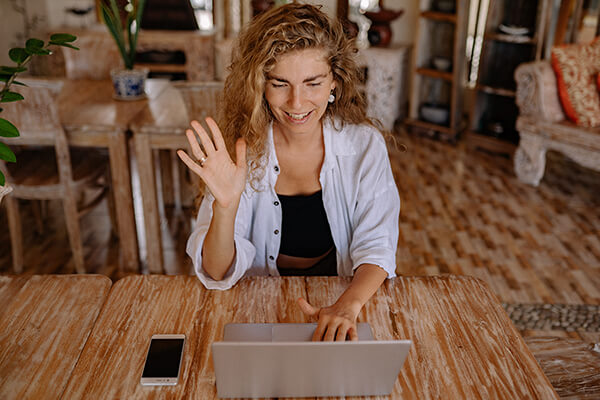 Woman waving at laptop.
