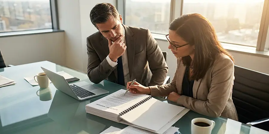 Professionals collaboratively reviewing a business sale agreement at a conference table