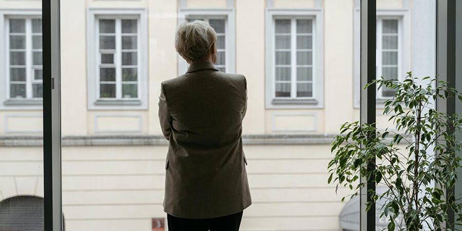 A woman dressed in a suit looking out of a window at a tall building.