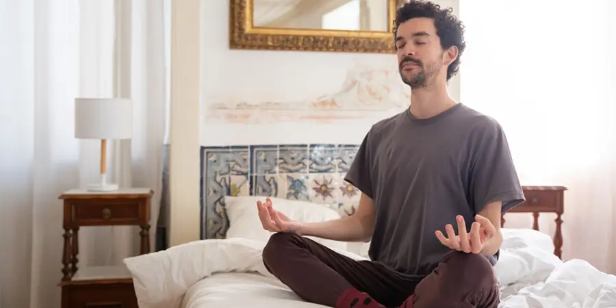 Person practicing mindfulness on an unmade bed.