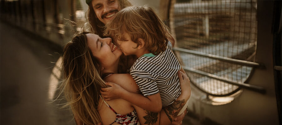 Happy parents hugging a young child.