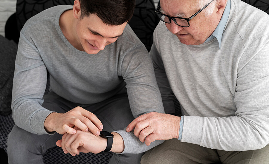 Younger man helping an older man use a smartwatch.
