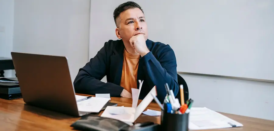 Person sitting alone at a desk, appearing thoughtful while dealing with everyday responsibilities.