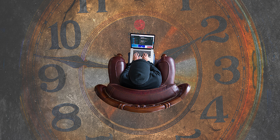 Person sitting on a chair using a laptop in the middle of a large clock.