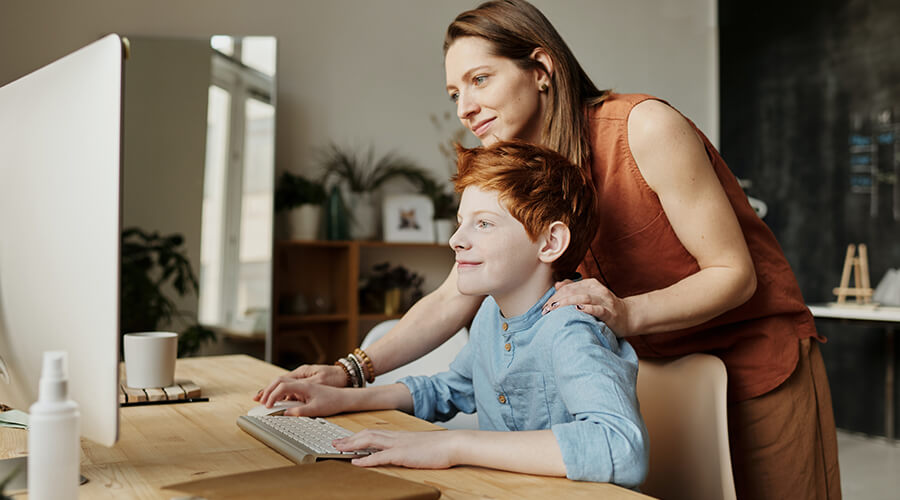 Woman teaching her son on a monitor.